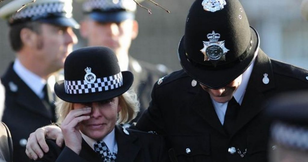 a police woman cries at a funeral